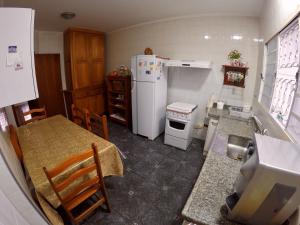 a kitchen with a table and a white refrigerator at Confortável casa de madeira in Poços de Caldas