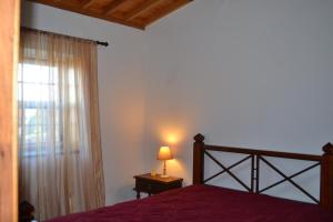 ein Schlafzimmer mit einem Bett und ein Fenster mit einer Lampe in der Unterkunft Adega Mendes in Porto Martins