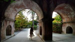 a woman walking down a street under an archway at Kinkaku in Kyoto