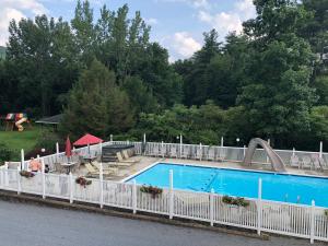 a white fence around a swimming pool with a slide at Lyn Aire Motel - Lake George in Lake George