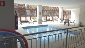 einen Pool in einem Gebäude mit Stühlen und einem Tisch in der Unterkunft Flat Vista Azul - Pedra Azul ES in Pedra Azul