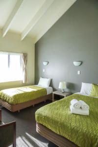 a hotel room with two beds and a window at Airport Manor Inn in Auckland