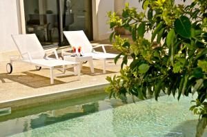 two white chairs sitting next to a swimming pool at Hotel Del Conte in Fondi