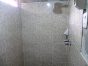 y baño con ducha y pared de azulejos. en HOSPEDAJE CAMPOS ELÌSEOS, en Oxapampa