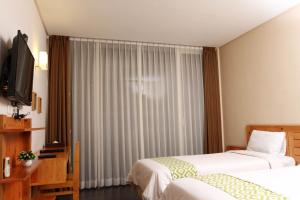 a hotel room with two beds and a television at Aventree Homestay in Malang +12 photos