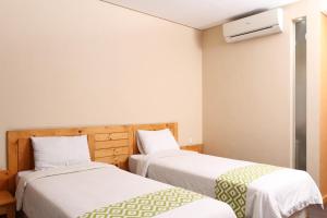 two beds in a small room with white walls at Aventree Homestay in Malang