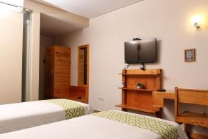 a bedroom with two beds and a tv on the wall at Aventree Homestay in Malang