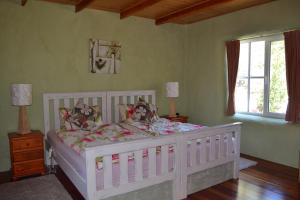 a bedroom with a white bed and two windows at Whispering Spirit Holiday Cottages & Mini Ponies in Franklin