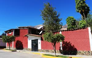 un edificio rojo y blanco con árboles delante de él en Casa Hospedaje"Los Capulies", en Carhuaz