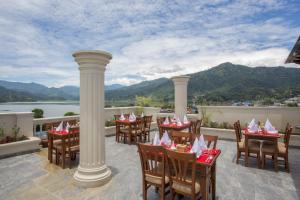 ein Restaurant mit Blick auf das Wasser und die Berge in der Unterkunft Hotel Portland in Pokhara