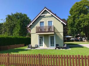 a green house with a balcony and chairs in the yard at Apartment Amber White in Nida