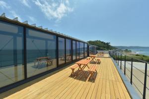 una terraza con bancos y mesas en la playa en Ocean Base Hagane, en Izumo
