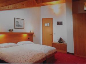 a bedroom with a large bed with a wooden headboard at Garni Meublè La Baita in Val di Zoldo