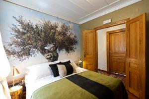 um quarto com uma cama com uma árvore na parede em Villa of the old olive oil factory em Ágios Konstantínos