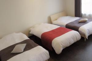 a room with three beds with different colored sheets at ウィークリー・マンスリー SORA in Miyako Island