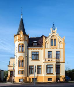 żółty budynek z wieżą na górze w obiekcie Hotel Knöpel w mieście Wismar