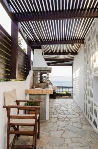 an outdoor patio with a fireplace and a wooden pergola at Asmini Villa in Pefki