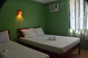two beds in a room with green walls at Sf Cantina in Bantayan Island