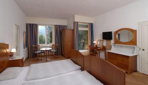 a bedroom with two beds and a table and a mirror at Mattenhof Resort in Interlaken