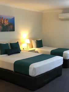 2 Betten in einem Hotelzimmer mit Grün und Weiß in der Unterkunft Tuckerbox Motor Inn in Gundagai + 30 Fotos