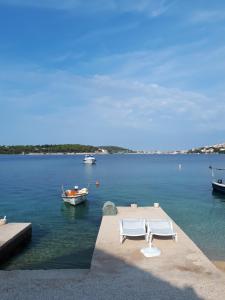 a couple of chairs and a boat in the water at Shell in Rogoznica