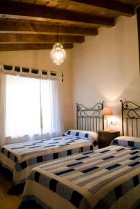 a bedroom with two beds and a chandelier at Casa rural La Rasa in Cabezas Altas