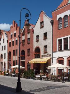 een straatlicht voor een gebouw met tafels en parasols bij Pensjonat M.F. in Elblag