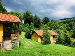 a small yellow house with a porch in a yard at Бунгала Дара in Kalofer