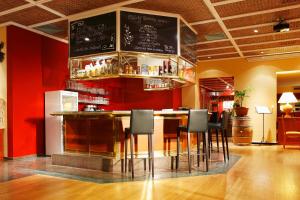 a bar in a restaurant with red walls and stools at Hapimag Resort Ascona in Ascona