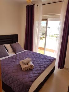 um quarto com uma cama roxa com toalhas em Appartement Résidence Yassmina em Tânger