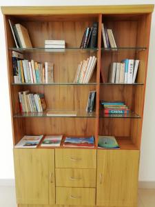 a wooden book shelf with books on it at La Grace Integral Retreat in Puducherry