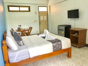a bedroom with a bed and a television and a table at Anchisa Mansion in Phayao