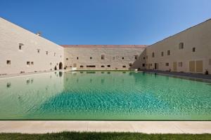 a large swimming pool in the courtyard of a building at Bernardas Convent Apartment in Tavira