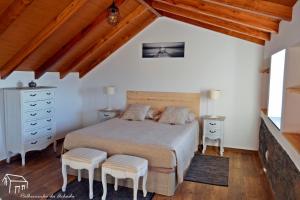 1 dormitorio con 1 cama y 2 taburetes en Palheirinho da Achada en Arco da Calheta