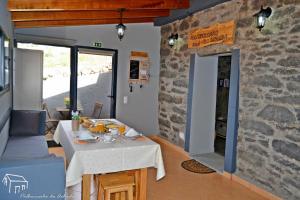 a dining room with a table and a stone wall at Palheirinho da Achada in Arco da Calheta +16 photos