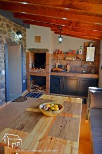 a kitchen with a bowl of fruit on a wooden table at Palheirinho da Achada in Arco da Calheta