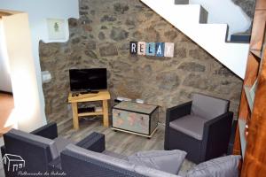 a living room with two chairs and a television at Palheirinho da Achada in Arco da Calheta