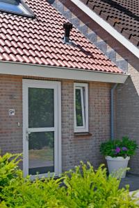 uma casa de tijolos com uma porta e duas janelas em IRISLAAN 9 em Oostkapelle