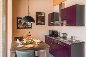 een keuken met paarse kasten en een tafel met eten erop bij Il Sogno Juniorsuiten - Appart. in Mombaruzzo