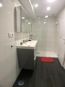 een witte badkamer met een wastafel en een douche bij Dotombori in Oleiros