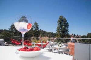 a glass of wine sitting on a table with a bowl of strawberries at Thomar Boutique Hotel in Tomar