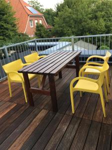 una mesa de madera y sillas amarillas en una terraza en Apothekerwohnung en Friesoythe