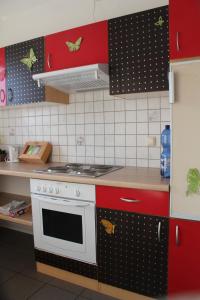 a kitchen with a white stove and red cabinets at Ferienwohnung Tropical in Vendersheim