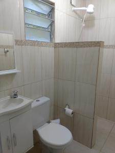 un bagno con un water, un lavandino e uno specchio di Ubatuba Suites Itamambuca a Ubatuba