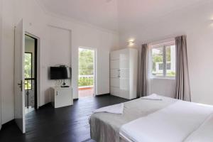 a white bedroom with a bed and a television at Mansions by Pinto Rosario in Bastora