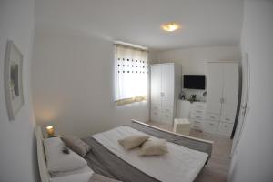 a white bedroom with a bed and a mirror at Apartment Lavanda Ruzmarin in Njivice +85 photos