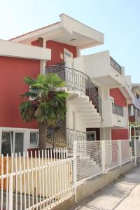 una casa roja con una valla blanca y una palmera en Apartments Durutović, en Bar