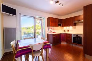 a kitchen with a table and chairs and a window at T3 Rez de Jardin,Piscine Privée in Saint-Cyr-sur-Mer