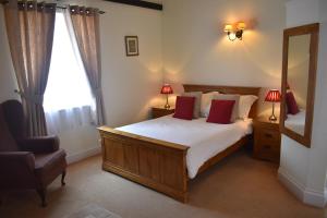1 dormitorio con cama, espejo y silla en Newcourt Barton en Cullompton