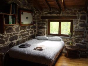 1 dormitorio con 1 cama grande en una pared de piedra en Preciosa cabaña pasiega restaurada en Espinosa de los Monteros